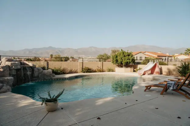 Family pool with a slide and rock water feature in an East Valley subdivision, Superstition Mountains on the horizon