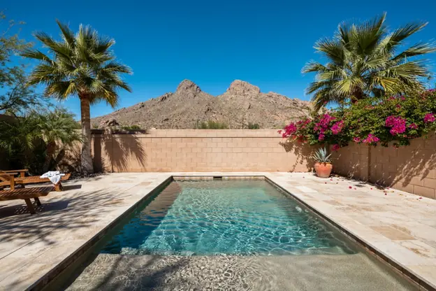 Backyard pool with a pebble finish in a Phoenix neighborhood, Camelback Mountain beyond the wall